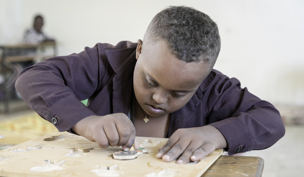A child with a learning disability doing a puzzle in class 