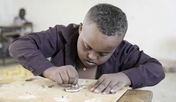 A child with a learning disability doing a puzzle in class